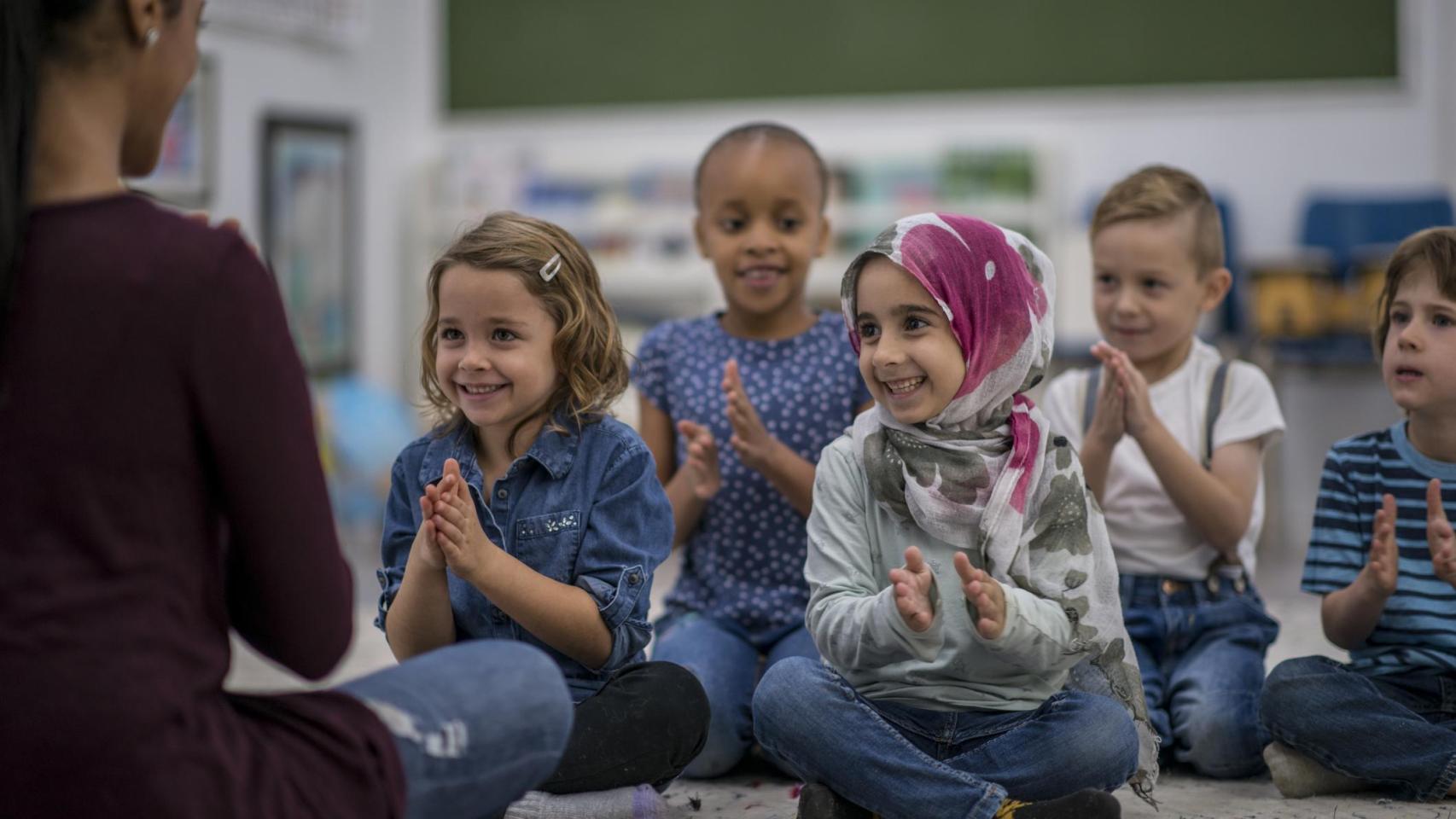 Un grupo de niños y niñas aplaudiendo en la escuela.