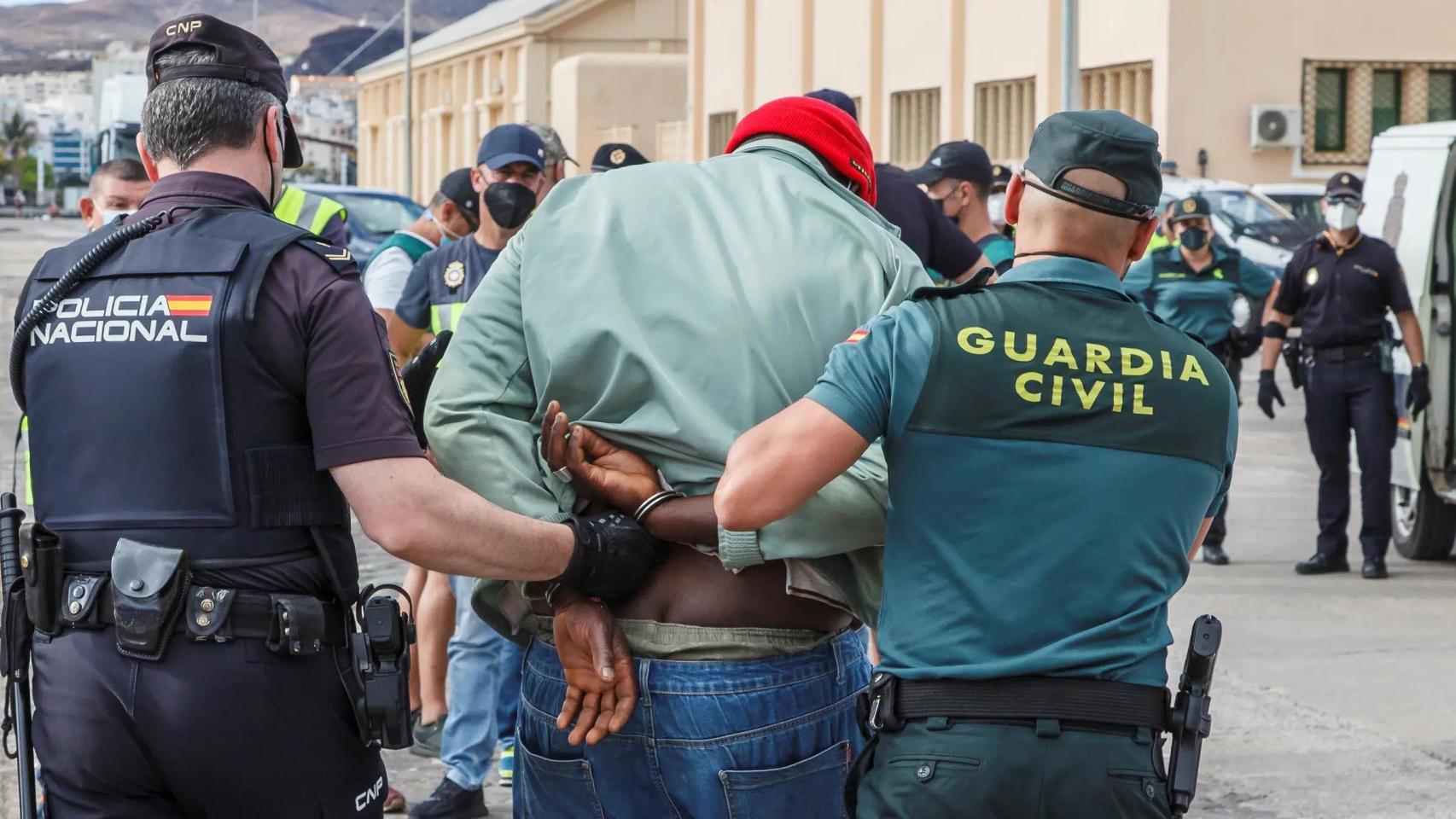 Un agente de Policía Nacional y uno de la Guardia Civil conducen a un detenido en una operación antidroga conjunta.