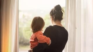 Una madre con su bebé mirando por la ventana.