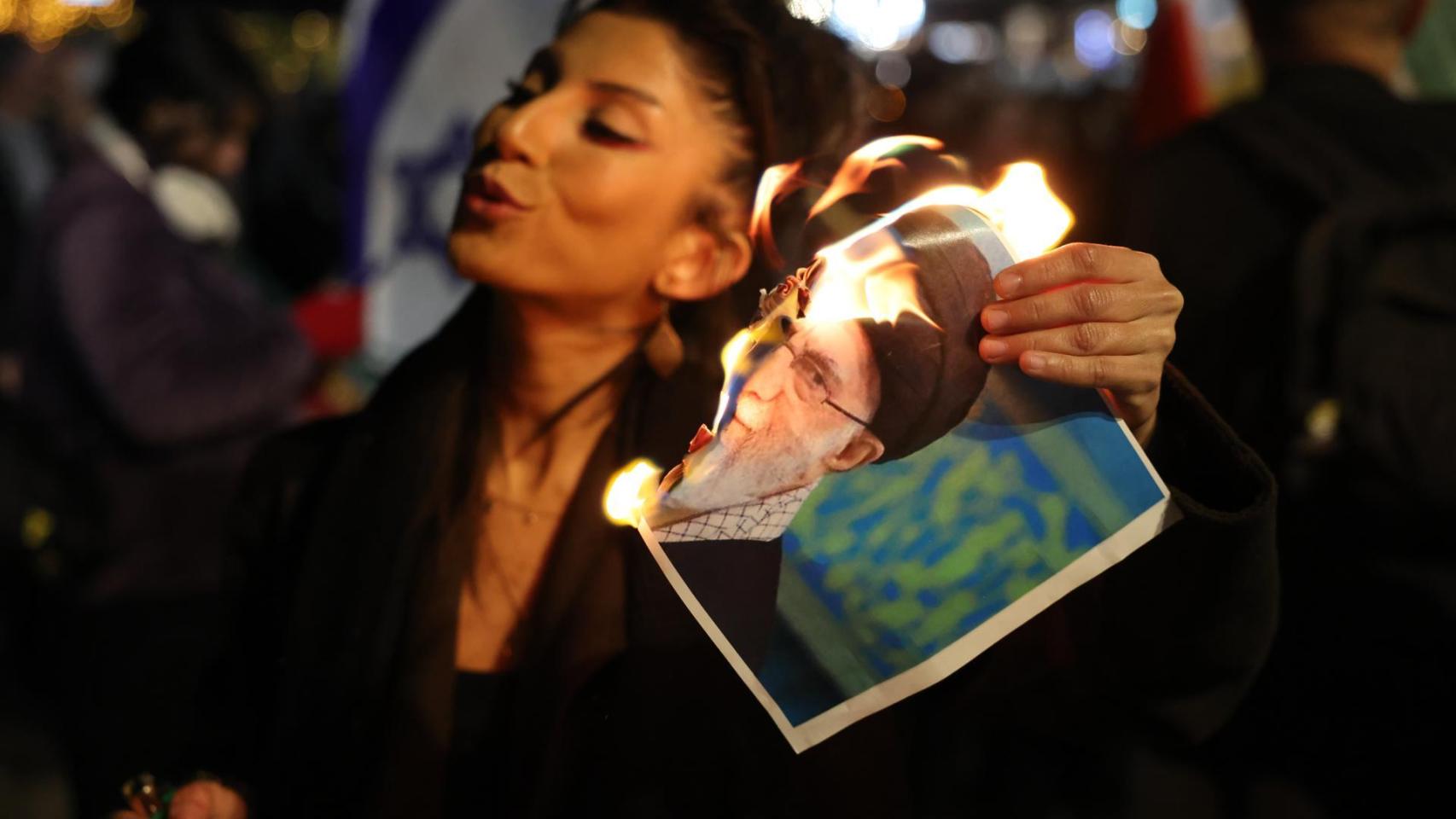 Una mujer quema una imagen del líder iraní Jamenei durante una protesta en apoyo al pueblo de Irán.