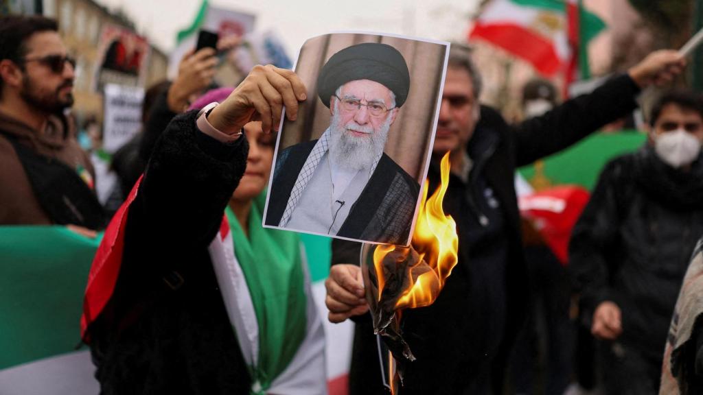 Una persona sostiene una imagen en llamas de Jamenei durante una protesta.