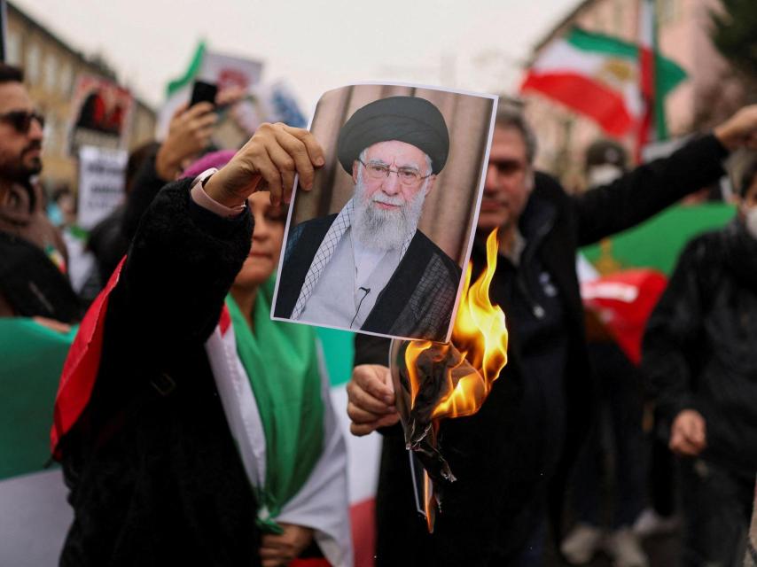 Una iraní sostiene una imagen en llamas de Jamenei durante una protesta.