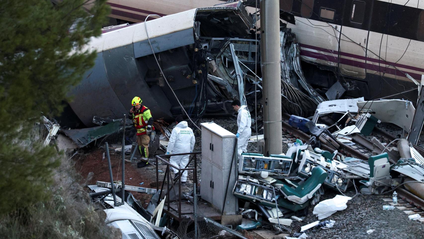 Un bombero y miembros de la Guardia Civil junto al tren Alvia de Renfe siniestrado.