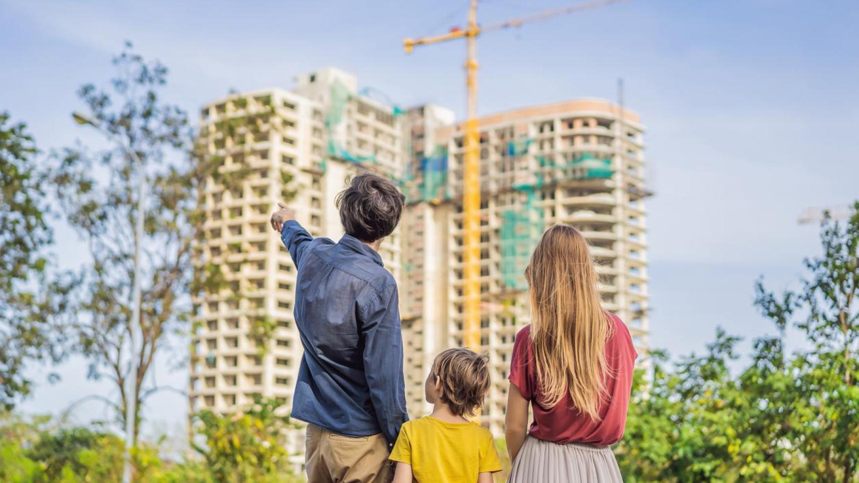 Una familia con hijos mirando su nueva casa en construcción.
