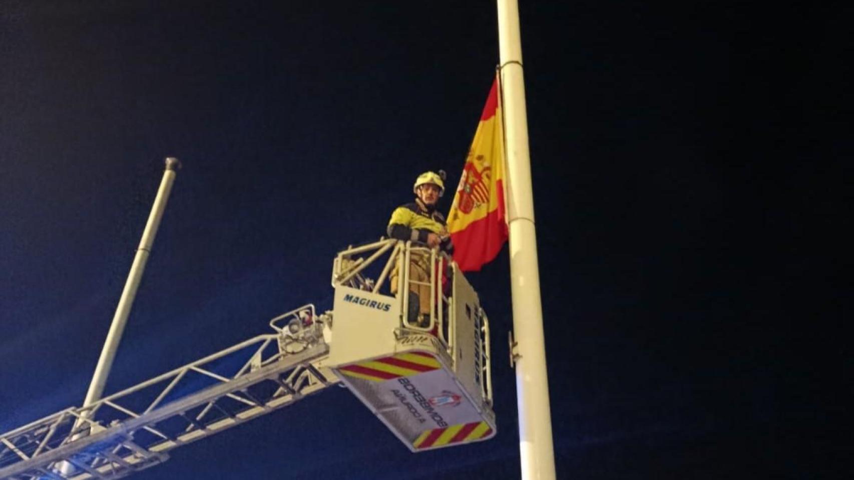 Imagen de los bomberos ondeando a media asta las banderas de la Coraza.