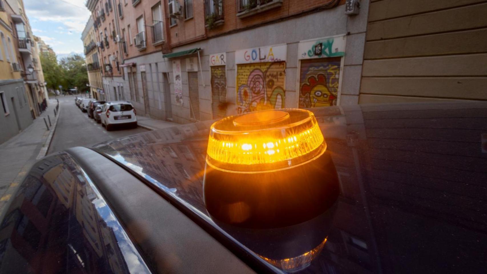 Un coche con la baliza V16 en una calle de Madrid.
