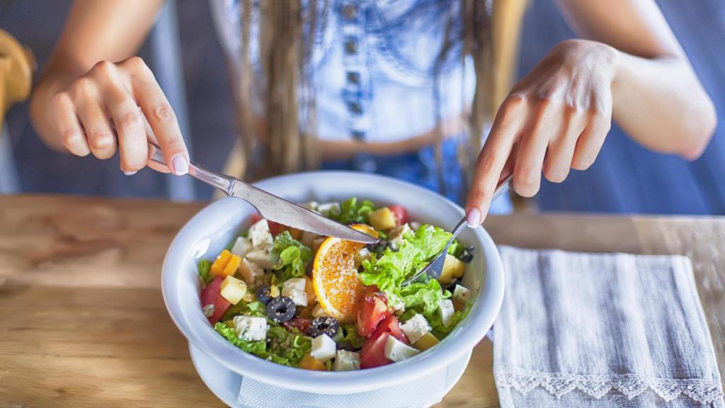 Una mujer comiendo una ensalada.