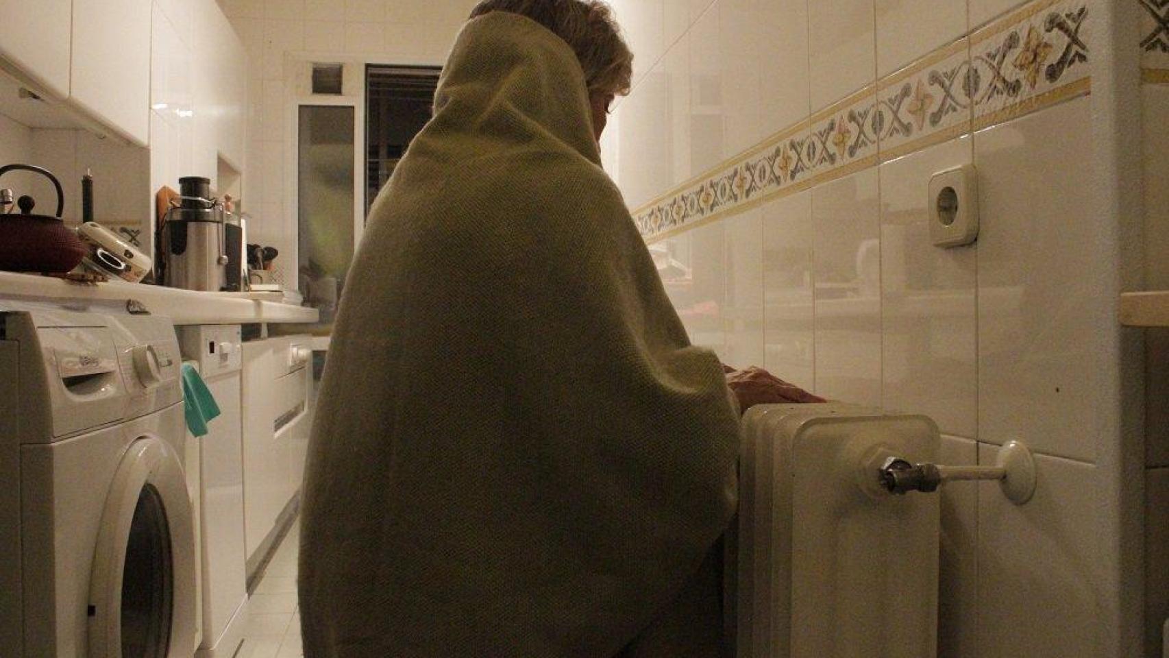 Una mujer con una manta para protegerse del frío, en imagen de archivo.