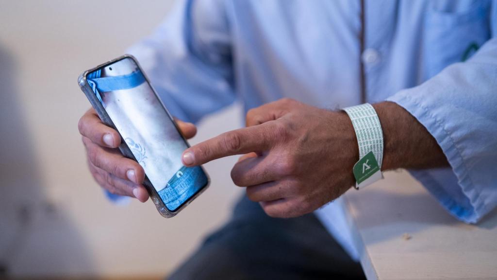 Emil Jonsson muestra en su teléfono una imagen de las lesiones en la espalda y las costillas sufridas durante el accidente ferroviario.