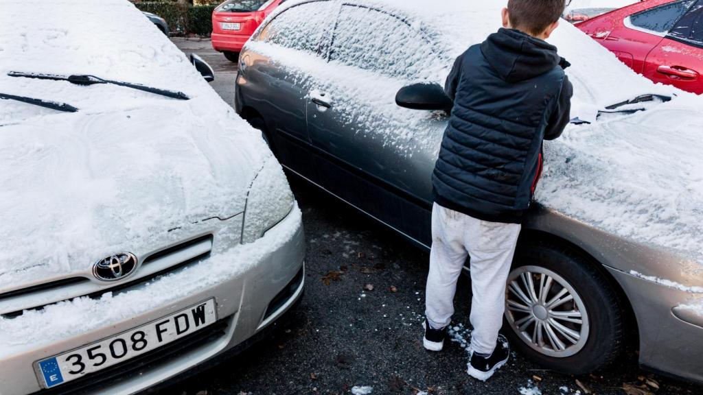 Un niño juega con la nieve que ha caído sobre un coche en Madrid.