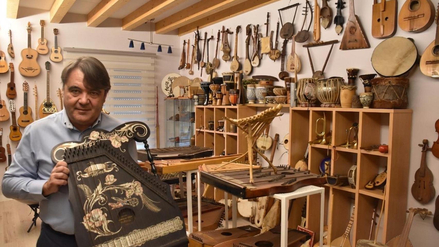 Luis Antonio González posa con una cítara que compró en Praga junto a su colección de casi 800 instrumentos tradicionales