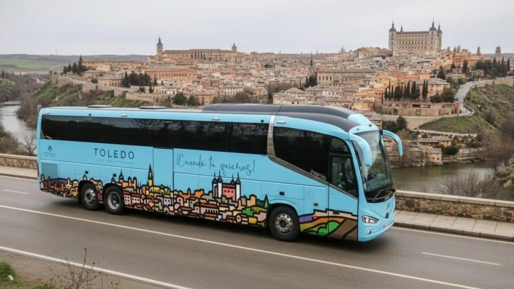 Un autobús promocional con Toledo al fondo.