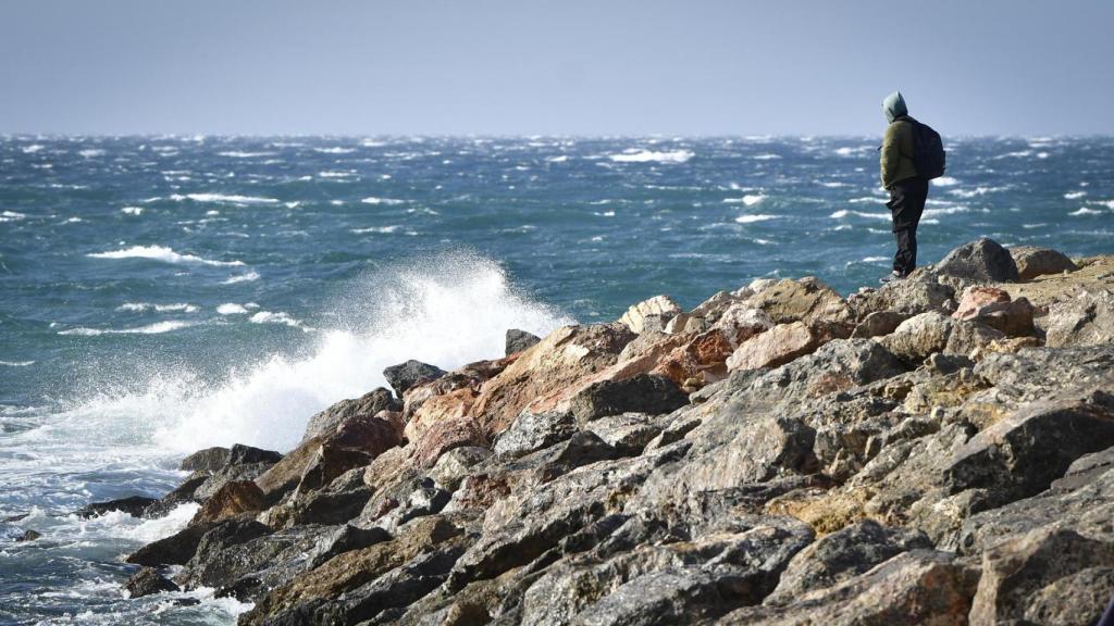Una persona observa las olas en Almería con fuertes vientos y fenómenos costeros.