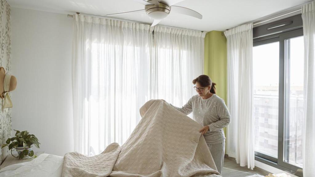 Una mujer en una habitación con ventilador de techo.