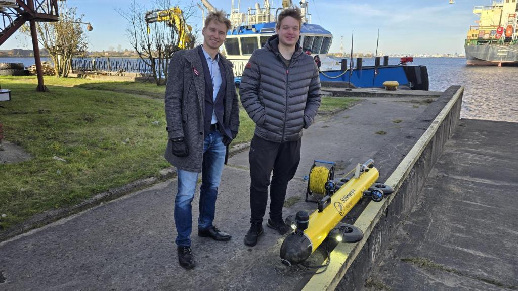 Eduards Lapiņš a la izda y Toms Rožkalns con su submarino en el puerto de Riga.