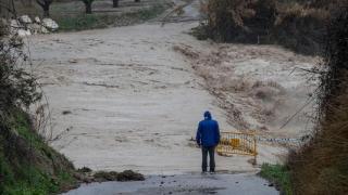 Un hombre observa junto una carretera inundada.