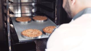 Un repostero introduce varias tartaletas valadar en un horno