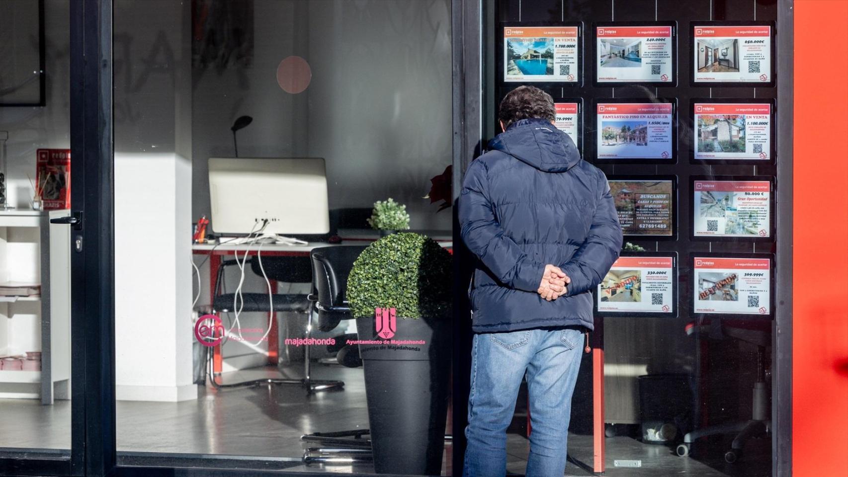 Un hombre mira el escaparate de una inmobiliaria.