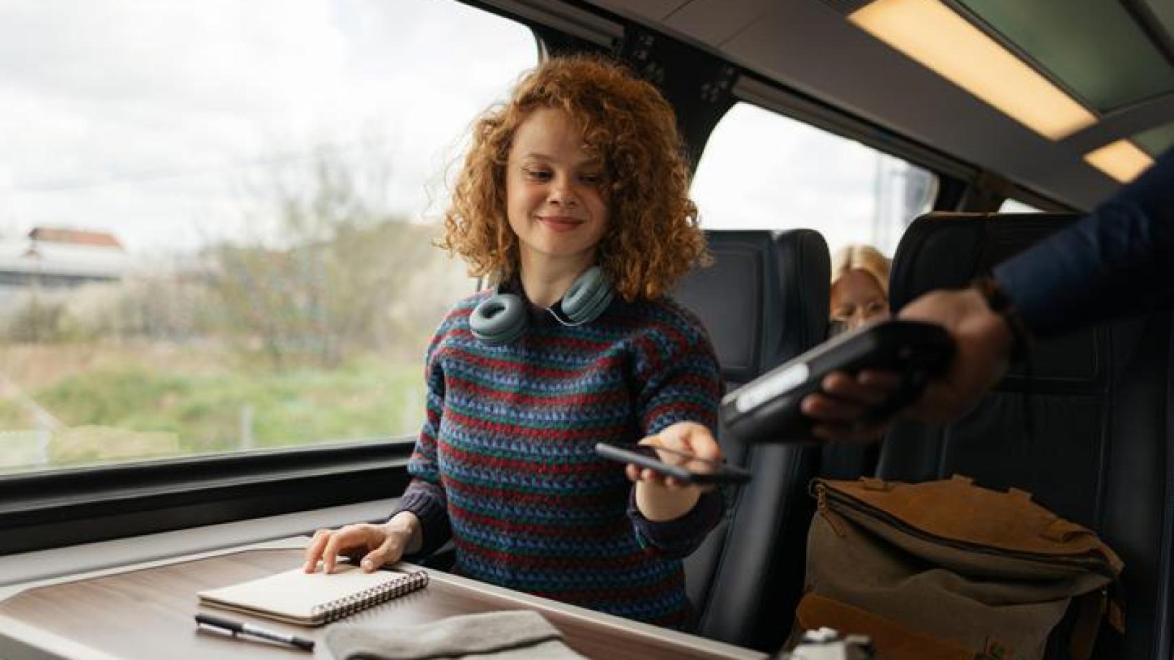 Mujer en el tren mostrando su billete al revisor.