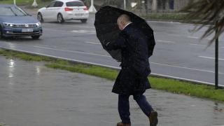 Un hombre con paraguas trata de refugiarse del viento y de la lluvia,en A Coruña.