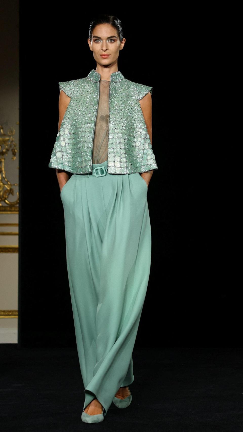 Modelo con un conjunto de pantalón fluido y chaleco metalizado.