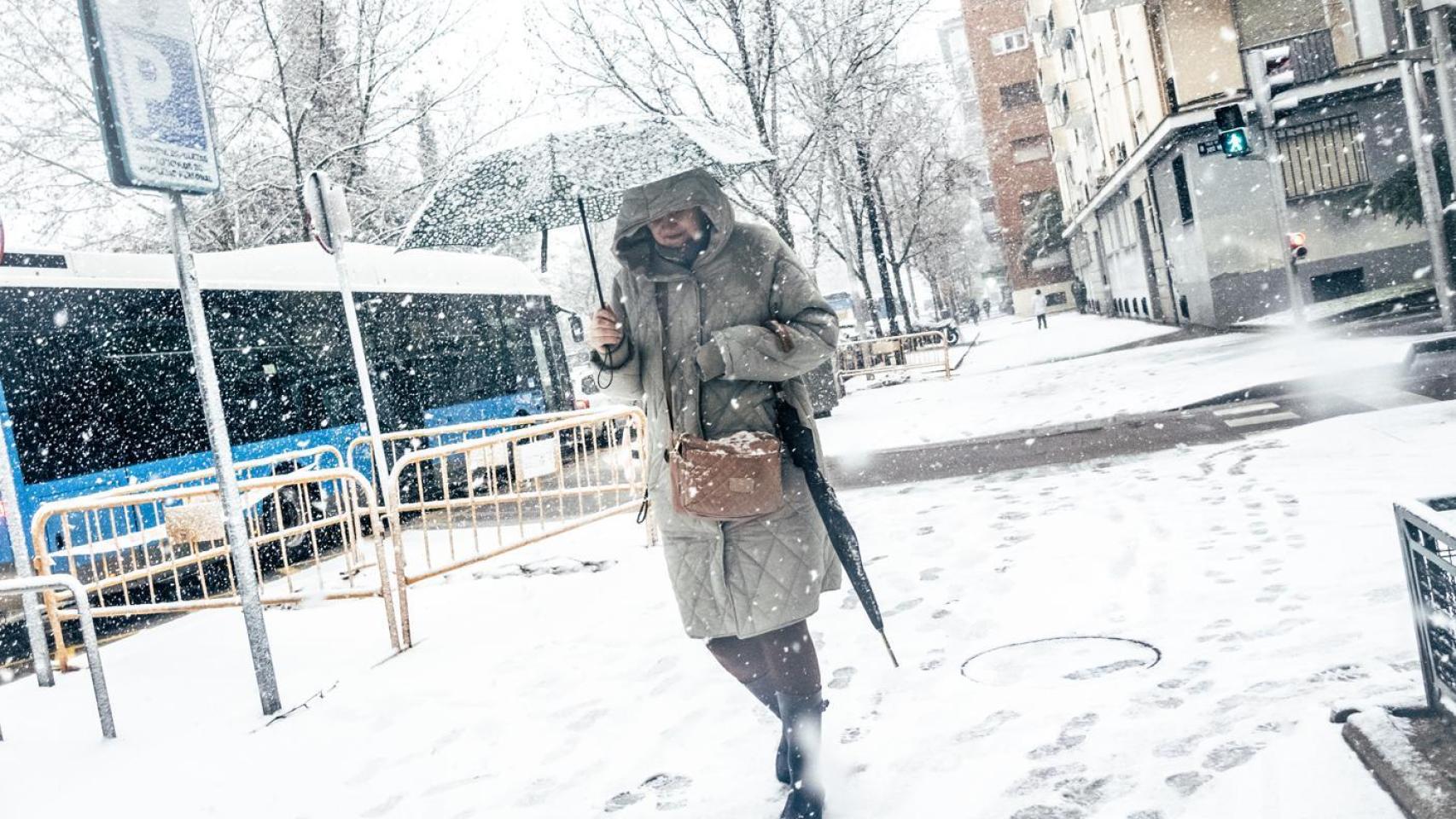 Una mujer camina bajo una intensa nevada en Madrid.