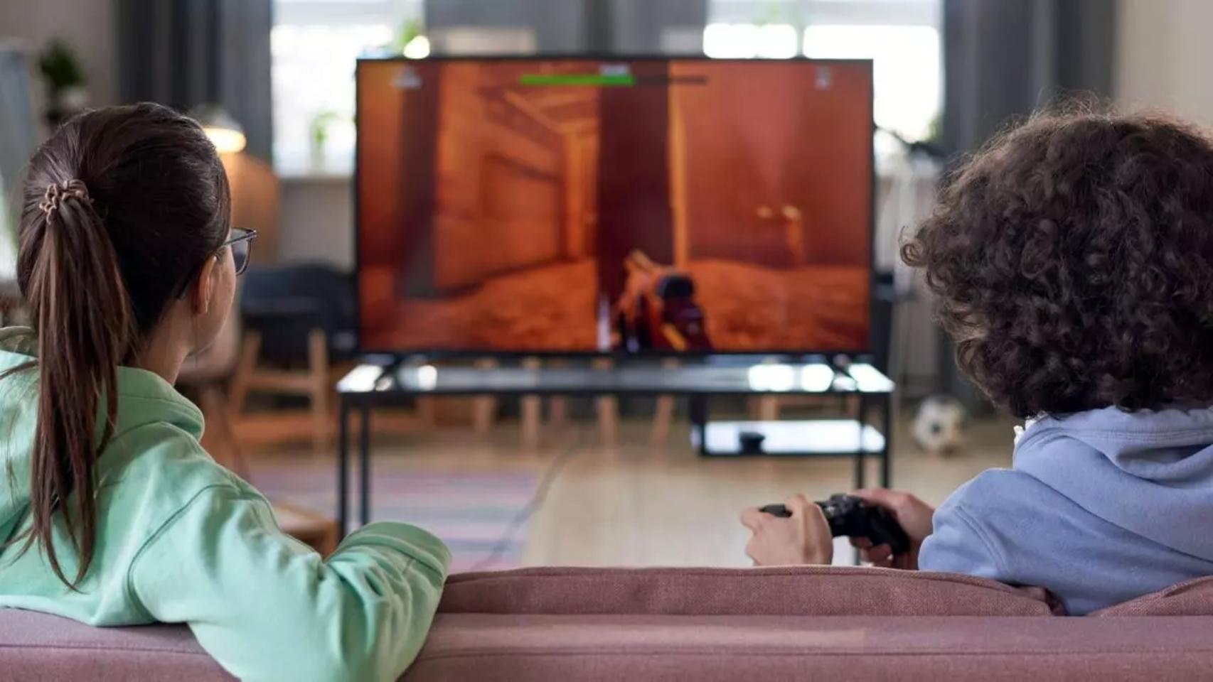 Dos adolescentes jugando a un videojuego en el salón de su casa.