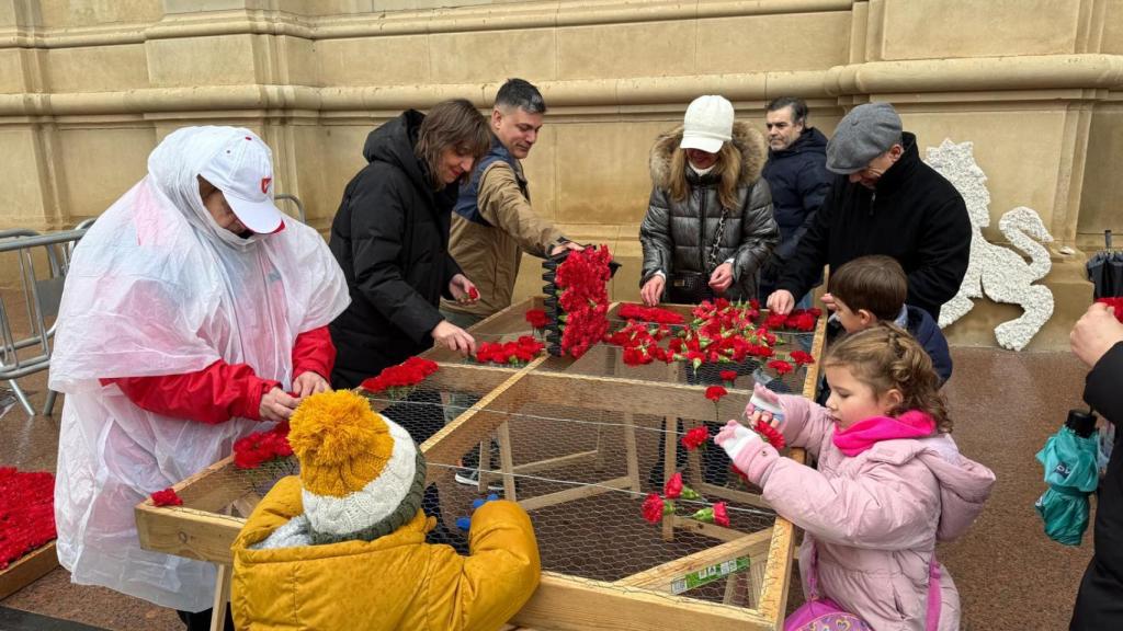 Lola Ranera y algunos pequeños colaboran en la bandera floral.