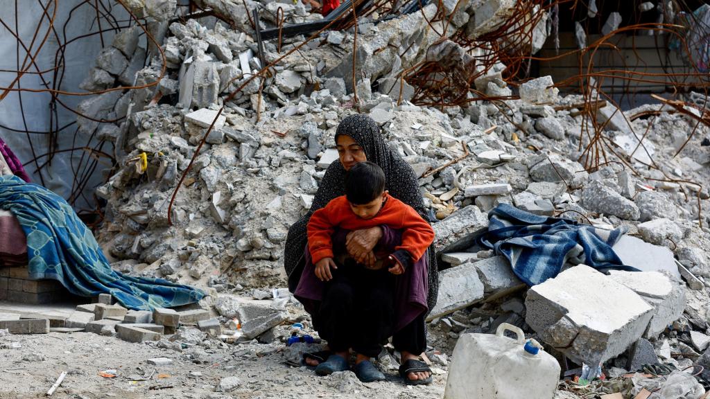 Palestinos caminan entre los escombros de edificios residenciales destruidos durante la guerra , en la ciudad de Gaza.
