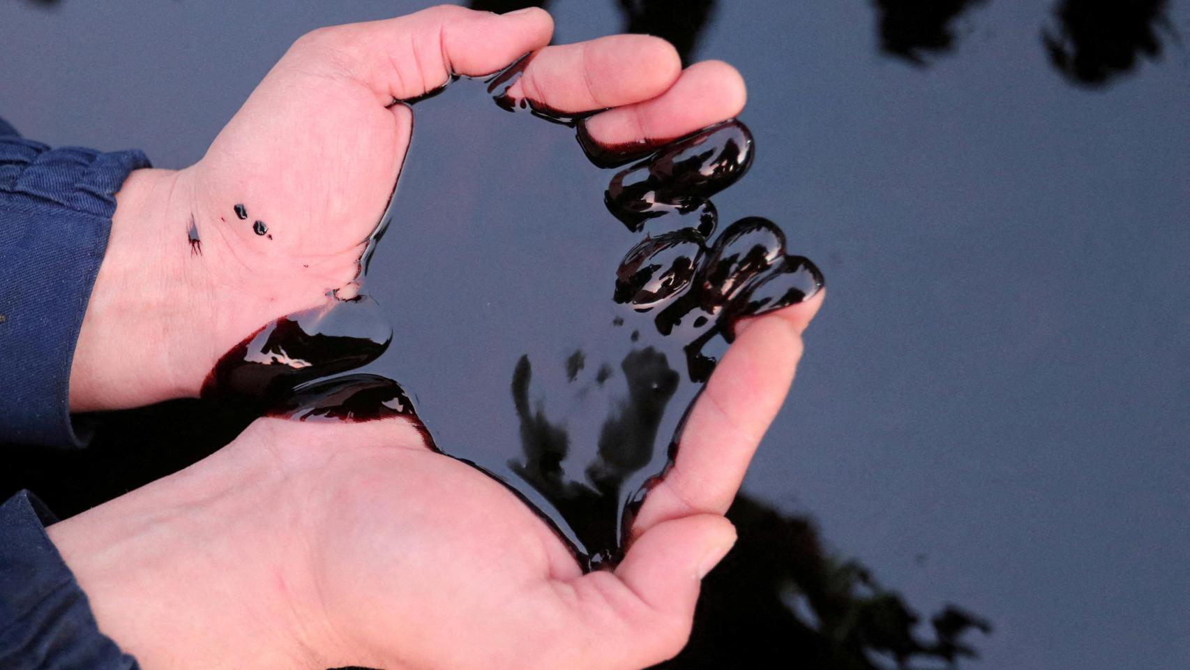 Un hombre recoge petróleo con sus manos en un campo petrolífero en Kazajistán.