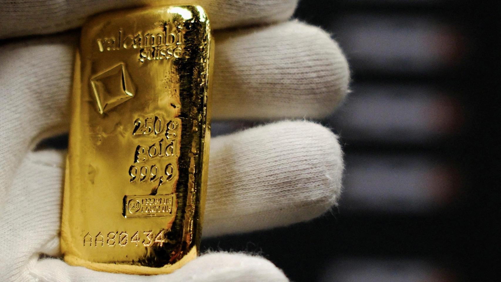 Un trabajador sostiene un lingote de oro en la tienda Barcelona Gold en Barcelona.