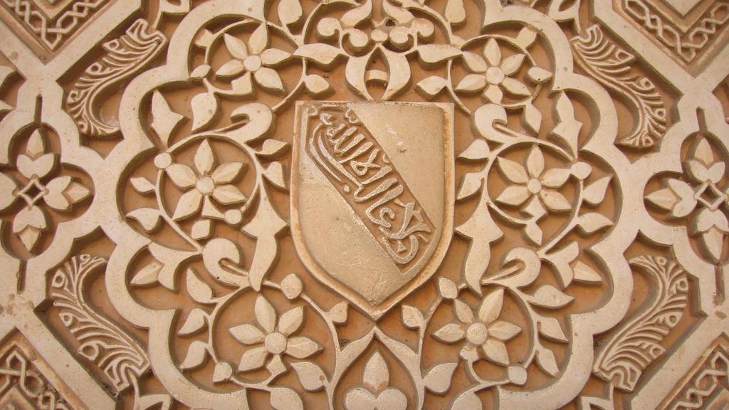 Escudo de la dinastía nazarí en el Palacio de La Alhambra, con la frase en medio.