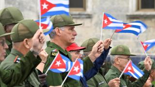 El presidente cubano Miguel Díaz‑Canel ondea una bandera cubana junto con otras personas durante una marcha frente a la Embajada de EEUU.