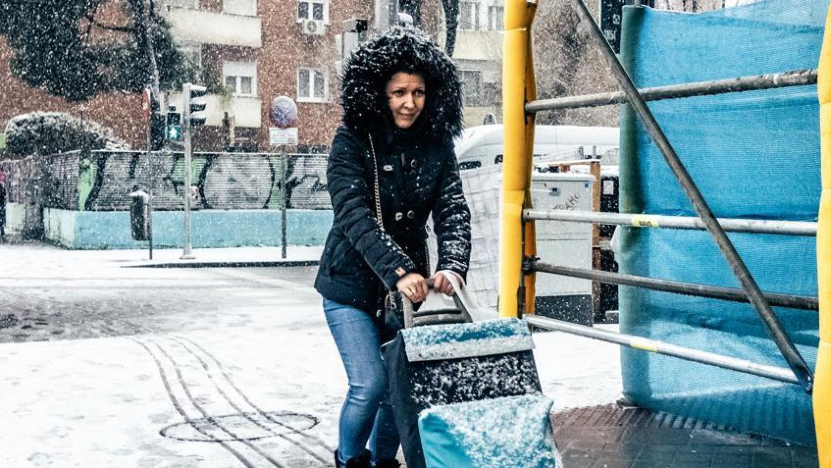 Una mujer se protege del frío mientras camina por Madrid.