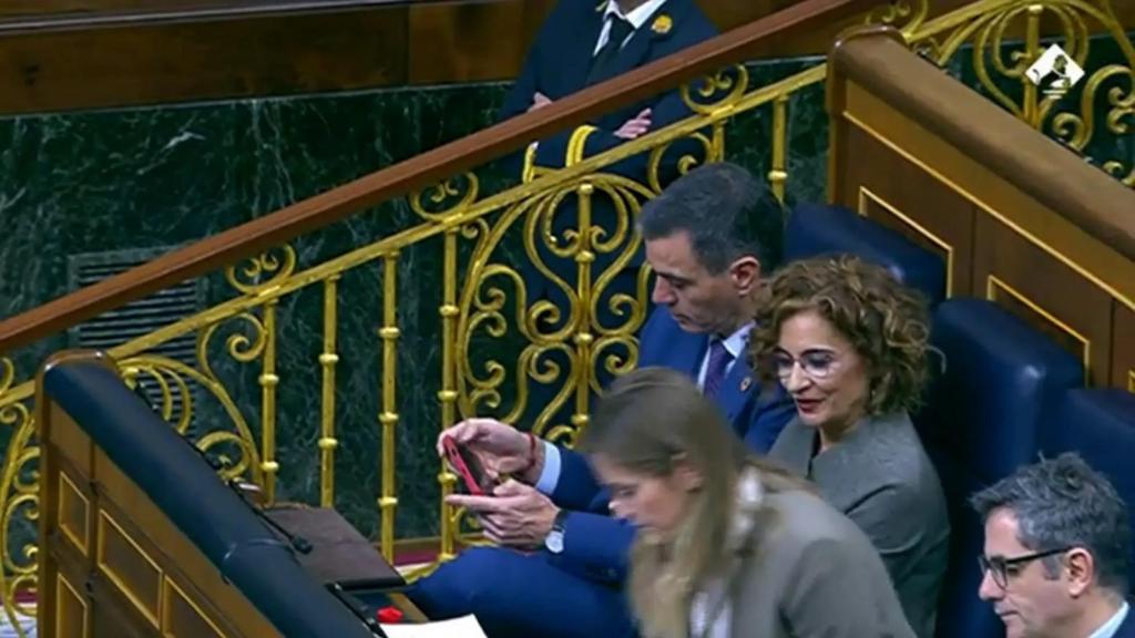 El presidente del Gobierno, Pedro Sánchez, utiliza el móvil durante una sesión en el Congreso de los Diputados.