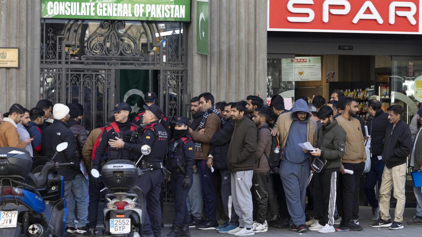 Inmigrantes hacen cola ante la puerta del consultado de Pakistán en Barcelona, para pedir el certificado de antecedentes a fin de acogerse a la regularización.