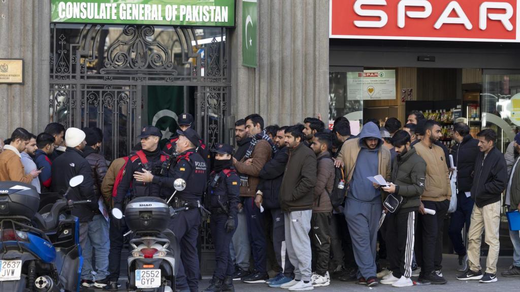 Inmigrantes hacen cola ante la puerta del consultado de Pakistán en Barcelona, para pedir el certificado de antecedentes a fin de acogerse a la regularización.