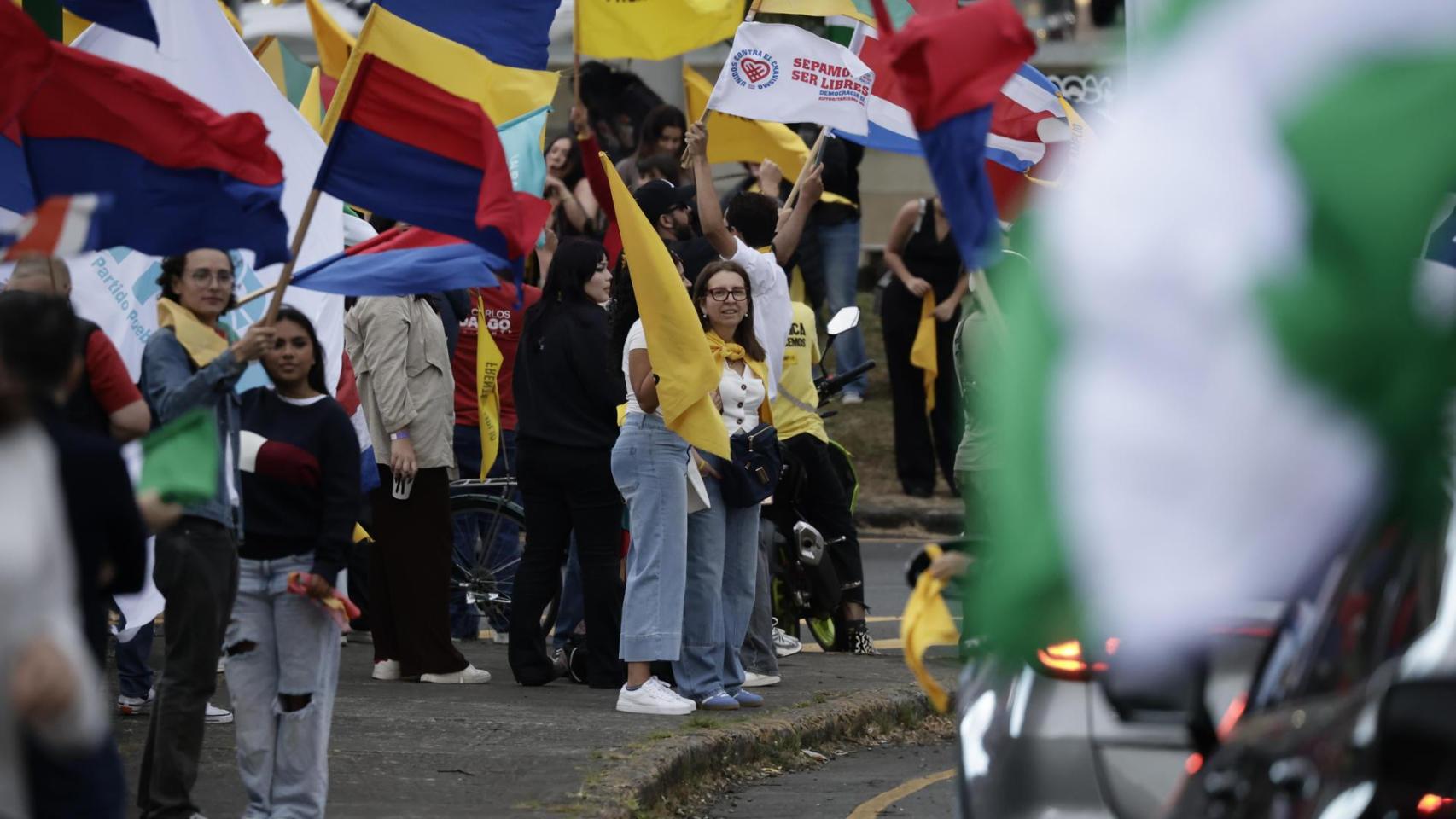 Simpatizantes de diferentes partidos políticos de Costa Rica sostienen banderas durante un recorrido este sábado, en San José (Costa Rica).
