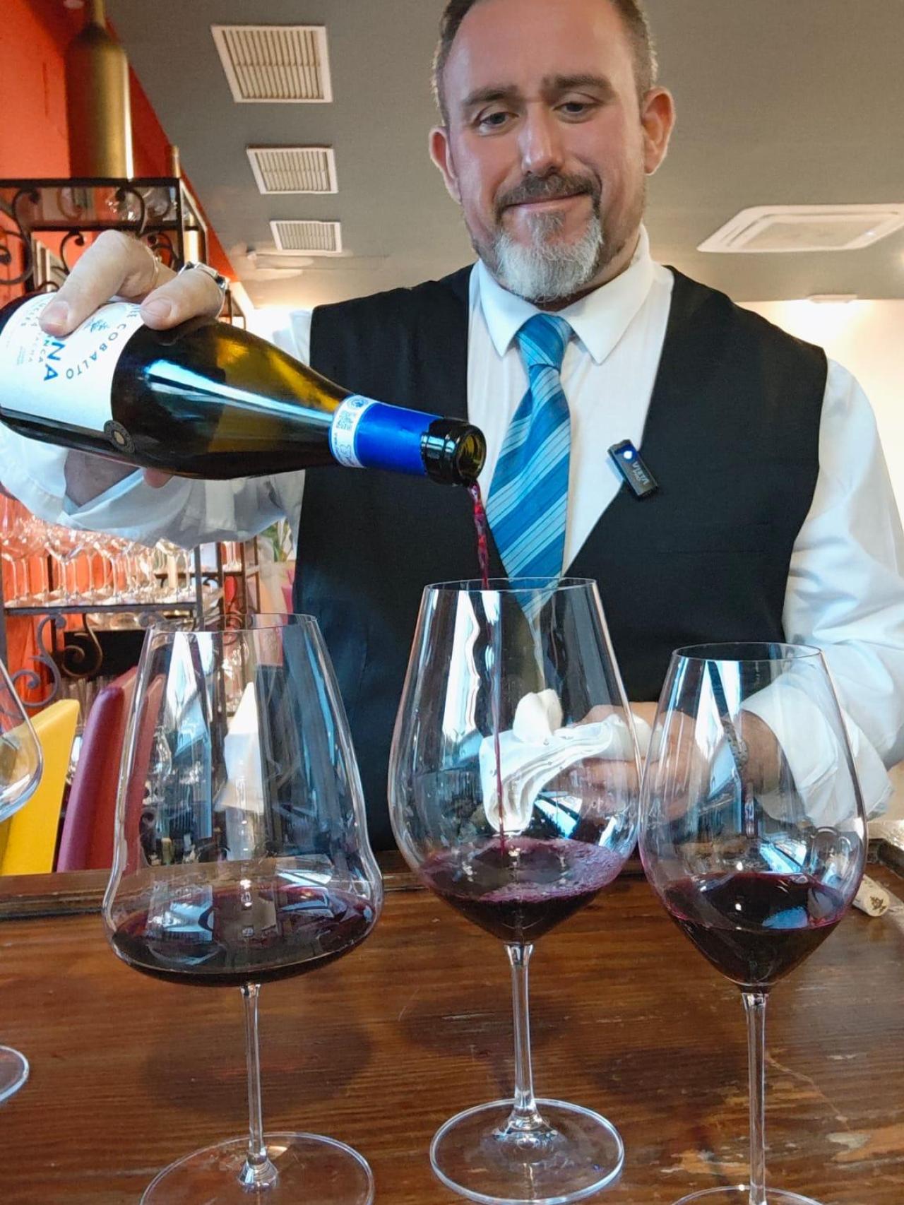 Adán sirviendo una copa de vino.