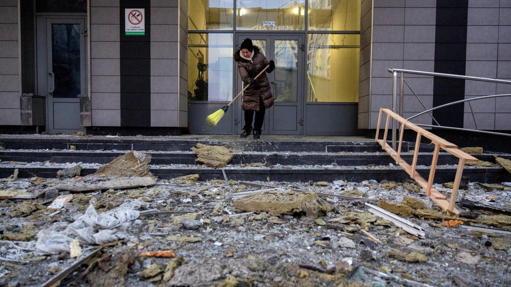 Una mujer barre los escombros provocados por un ataque ruso sobre Kiev.
