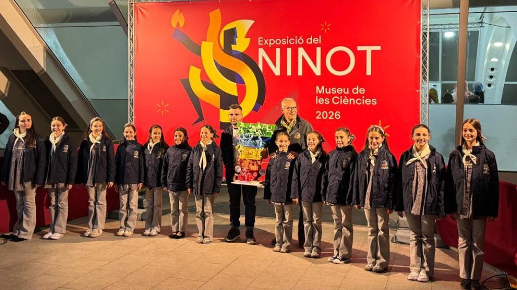 Fallera mayor infantil y corte de honor junto al 'ninot' de la falla municipal infantil. EE