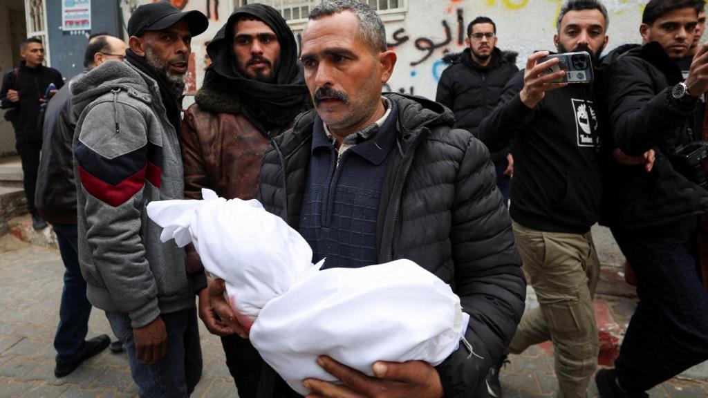 Un hombre gazatí lleva en sus brazos el cadáver de un niño muerto en un ataque israelí en Gaza este miércoles.