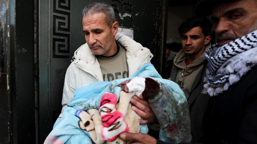 Un hombre sostiene en brazos a un bebé tras los ataques de Israel en Gaza.