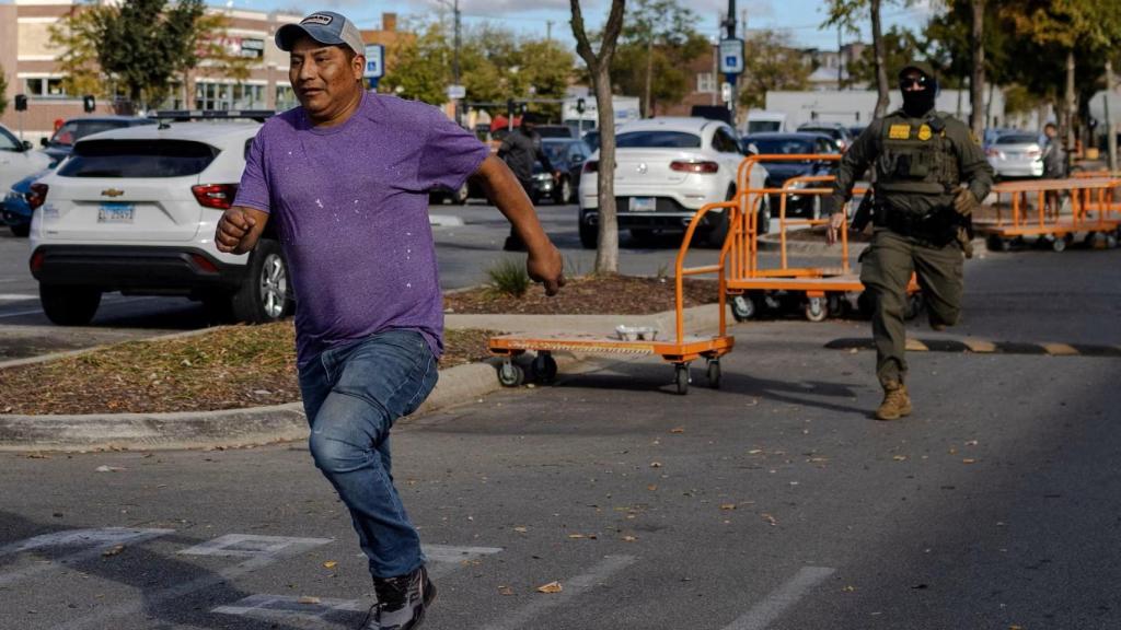 Un agente federal persigue a un hombre en el estacionamiento de un Home Depot en Chicago, el 11 de octubre.