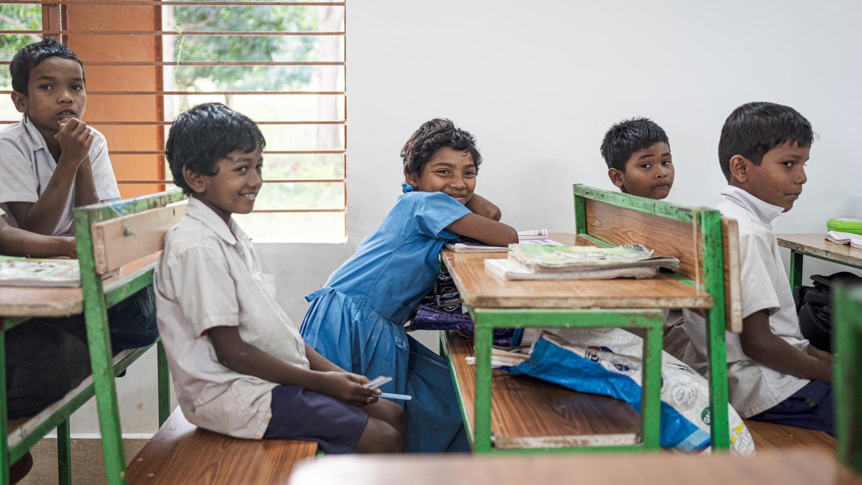 Una niña de la comunidad, sentada junto a sus compañeros de clase.
