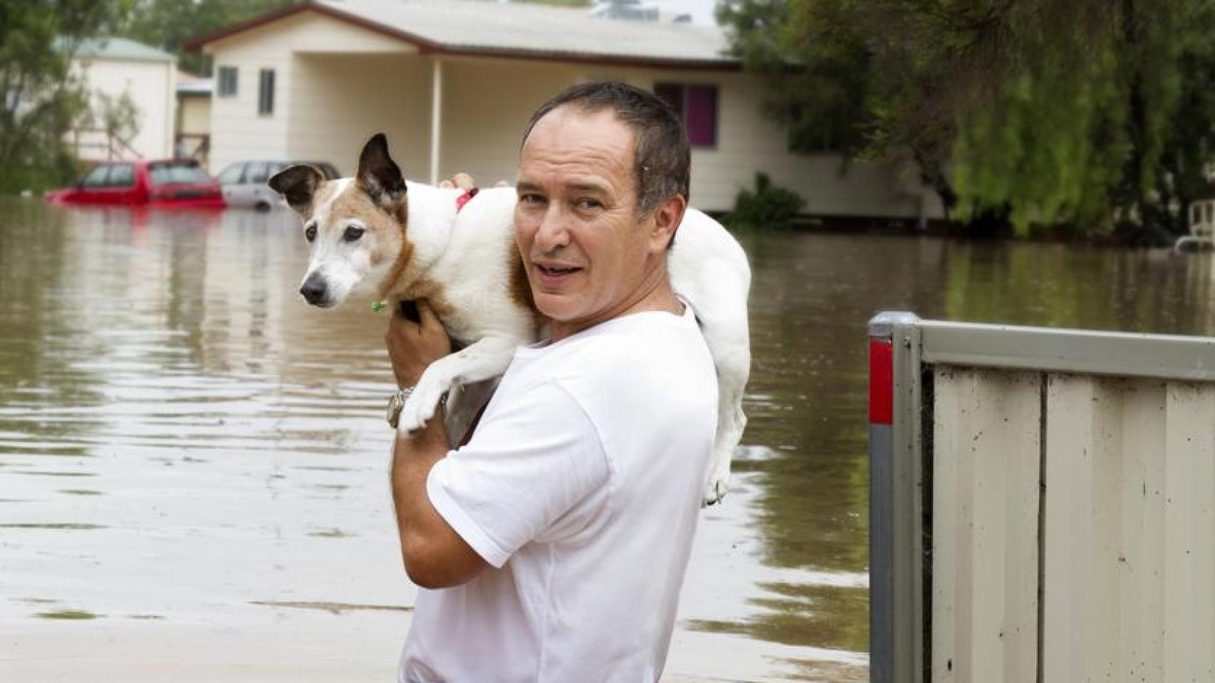 Un hombre rescatando un perro de una inundación.