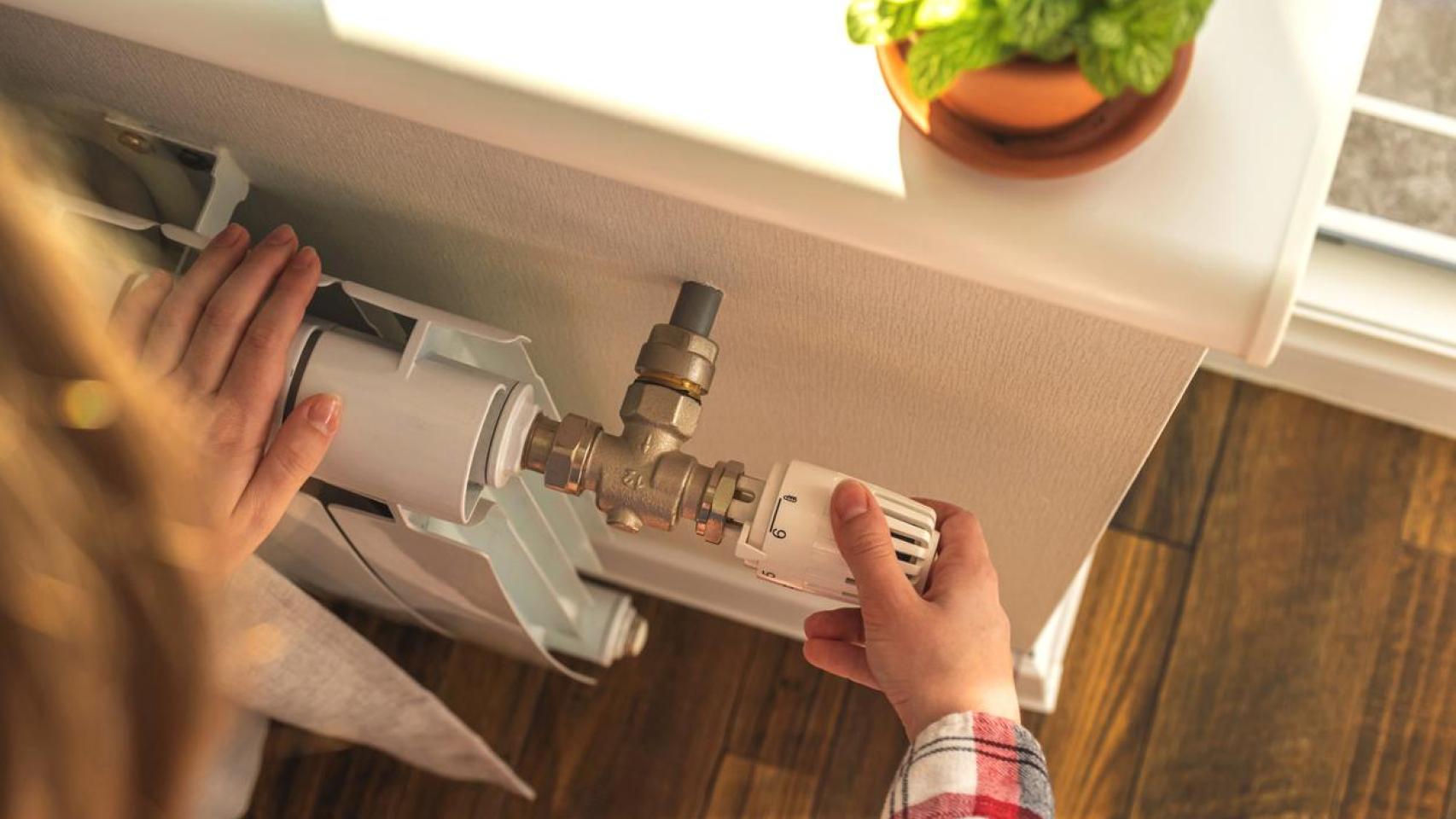 Mujer ajustando la válvula de un radiador.