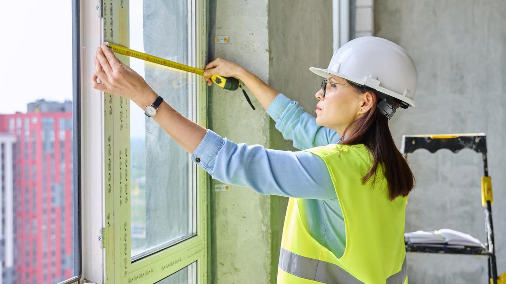 Una mujer con casco de seguridad cambiando las ventanas.
