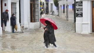 Una vecina de Grazalema (Cádiz) camina por una calle inundada debido a las intensas lluvias.