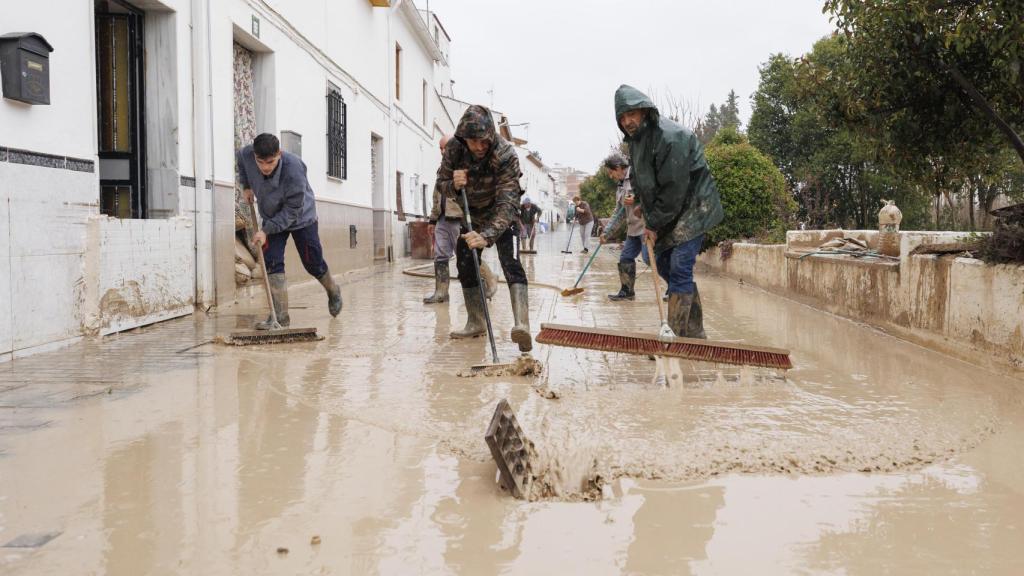 Vecinos de Villanueva Mesía (Granada) se afanan en sacar el agua y barro de sus casas tras la crecida del Río Genil por el paso de la borrasca 'Leonardo'.